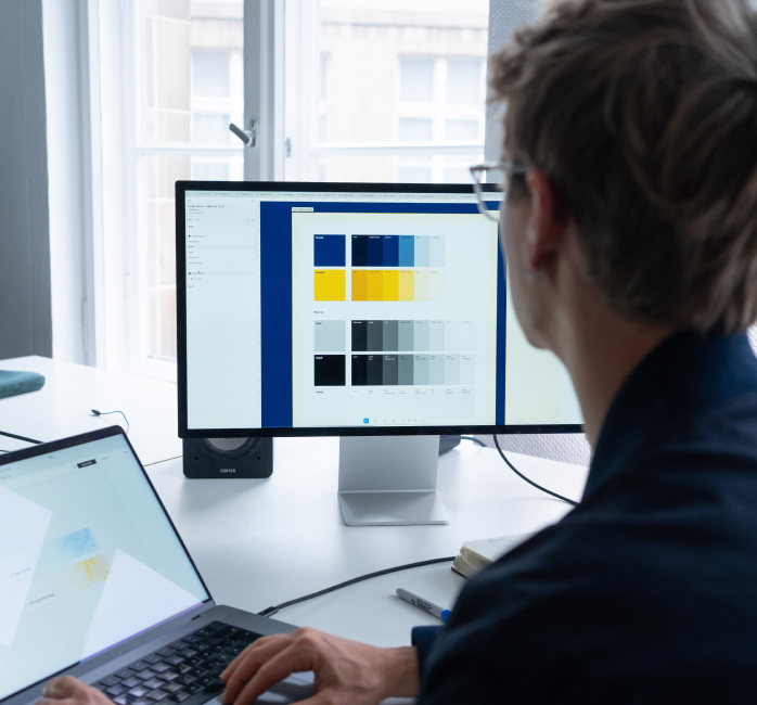 Designers from Ennostudio working on a color palette and UI components for a digital product on a large monitor.