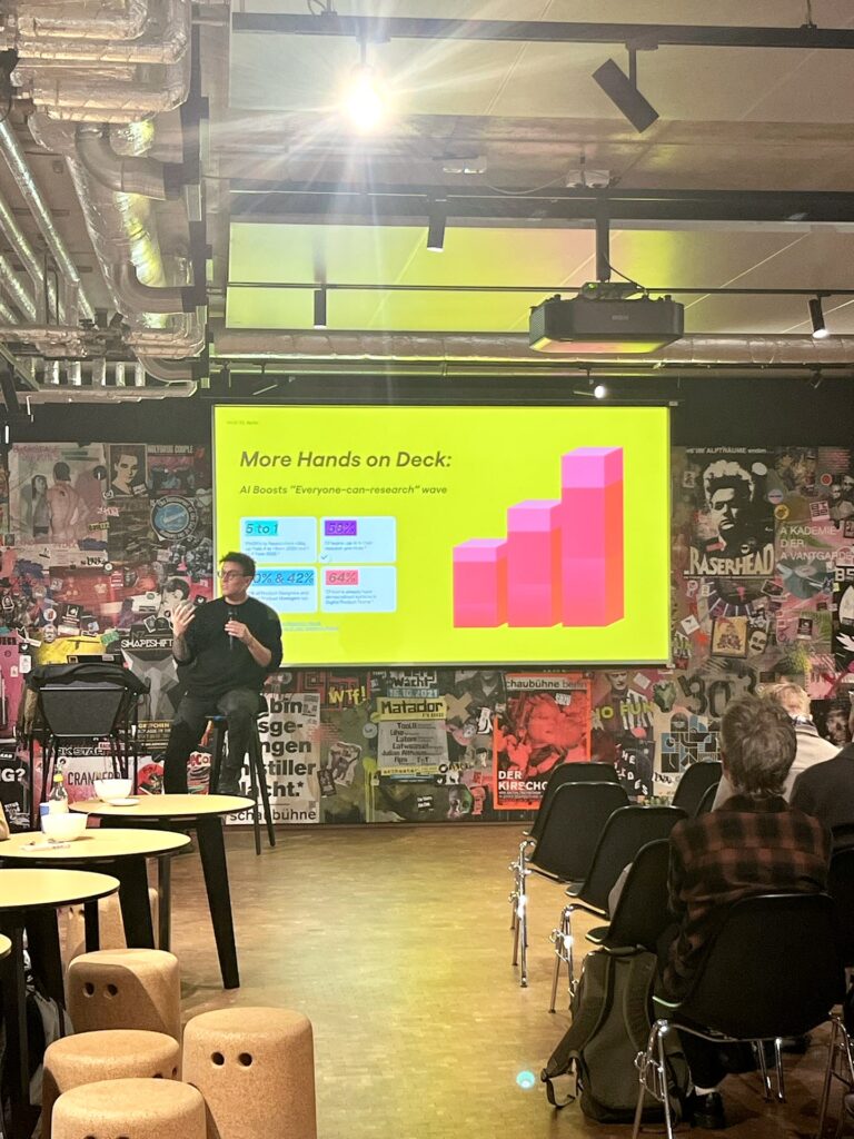 Speaker from Miro presents the newest paradigm shift in UX research at a World Usability Day session, standing in front of a bright slide with bar chart visuals